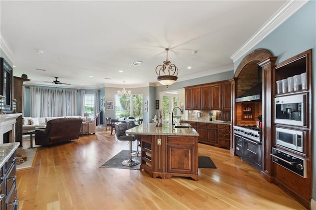 kitchen featuring crown molding, sink, an island with sink, and light hardwood / wood-style flooring