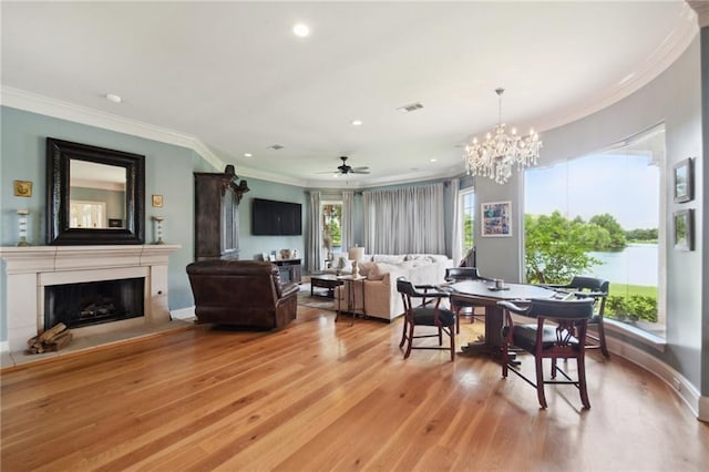 dining room with ceiling fan with notable chandelier, crown molding, and light hardwood / wood-style flooring