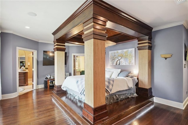 bedroom featuring ornate columns, crown molding, ensuite bath, and hardwood / wood-style flooring