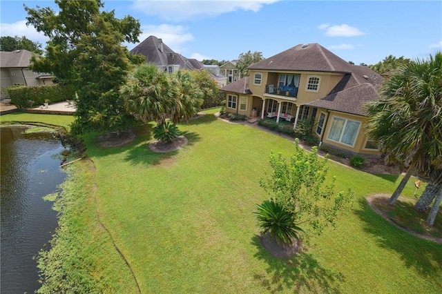 rear view of house with ceiling fan, a balcony, and a yard