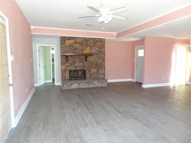 unfurnished living room with a ceiling fan, visible vents, a stone fireplace, and wood finished floors