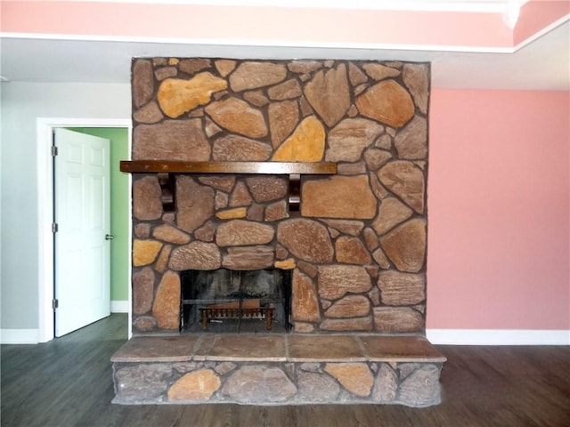 room details with a stone fireplace, baseboards, and wood finished floors