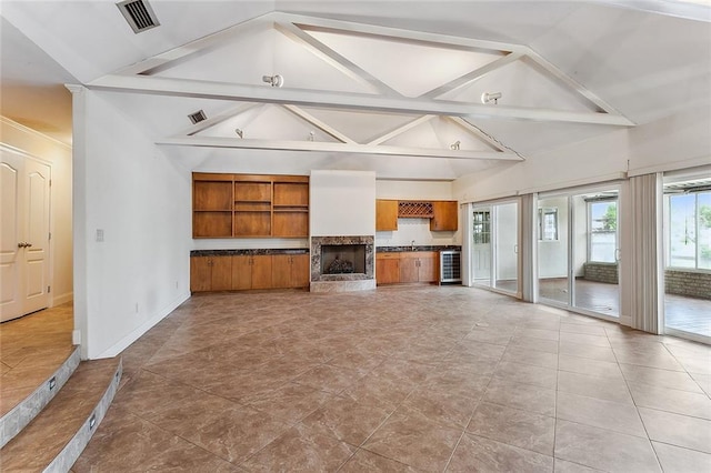 unfurnished living room with beamed ceiling, sink, and high vaulted ceiling