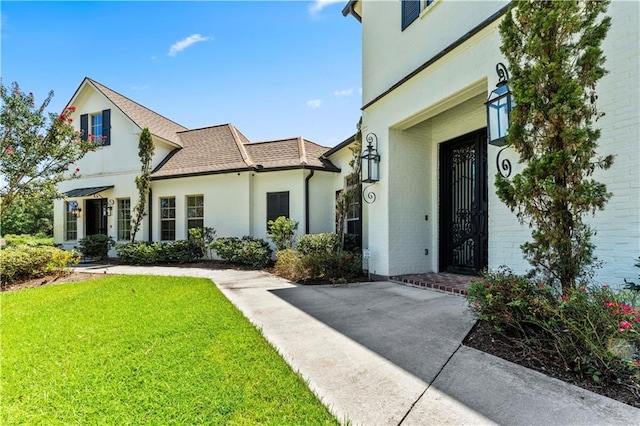 view of exterior entry featuring a lawn