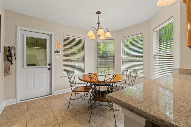 dining space with light tile patterned floors, baseboards, and a notable chandelier
