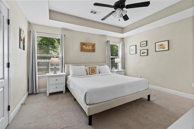 carpeted bedroom featuring ceiling fan and a raised ceiling