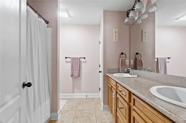 bathroom with a sink, baseboards, double vanity, and tile patterned flooring