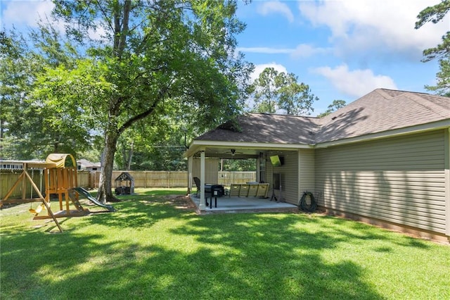 view of yard with ceiling fan, a playground, a fenced backyard, and a patio area