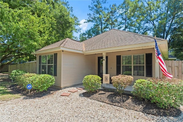 view of front of property with fence, covered porch, and roof with shingles