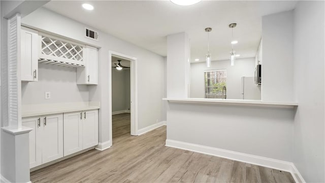 kitchen with kitchen peninsula, white cabinets, white fridge, and light wood-type flooring