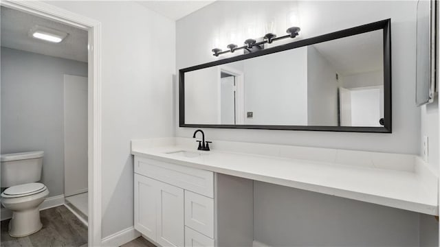 full bath with toilet, baseboards, wood finished floors, and vanity