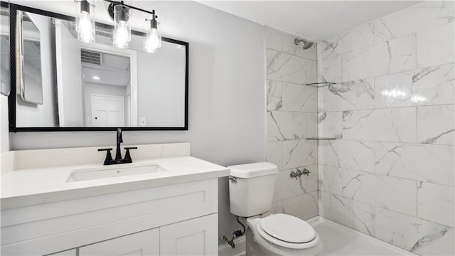 bathroom with visible vents, vanity, toilet, and tiled shower