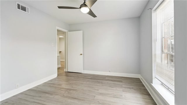 unfurnished room with a ceiling fan, light wood-type flooring, visible vents, and baseboards