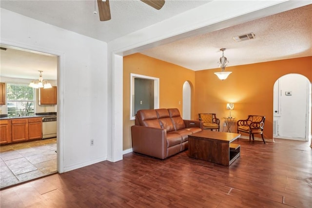 living room with ceiling fan, sink, dark hardwood / wood-style floors, and a textured ceiling