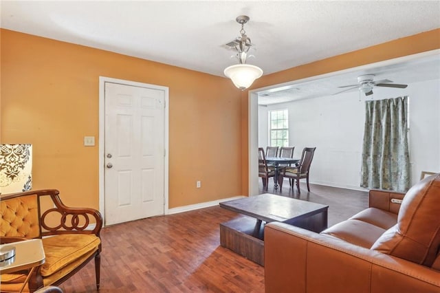 living room featuring ceiling fan and dark wood-type flooring