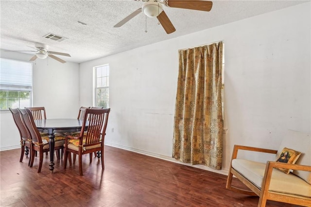 dining room featuring ceiling fan, dark hardwood / wood-style floors, a textured ceiling, and a wealth of natural light