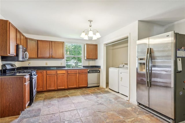 kitchen featuring appliances with stainless steel finishes, washing machine and dryer, pendant lighting, sink, and an inviting chandelier