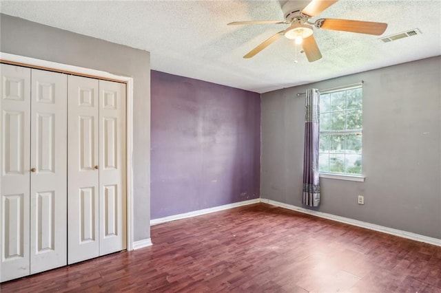 unfurnished bedroom featuring hardwood / wood-style flooring, ceiling fan, a textured ceiling, and a closet