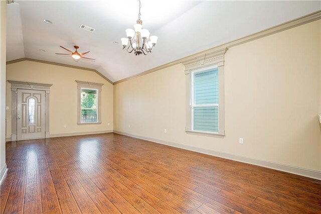 empty room featuring vaulted ceiling, ceiling fan with notable chandelier, hardwood / wood-style floors, and crown molding