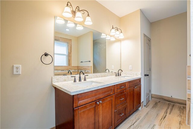 bathroom with double vanity, a chandelier, and hardwood / wood-style floors