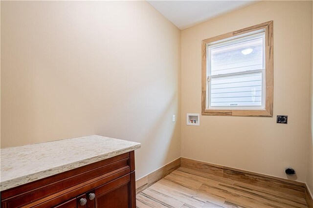 washroom featuring hookup for an electric dryer, light hardwood / wood-style flooring, cabinets, and hookup for a washing machine