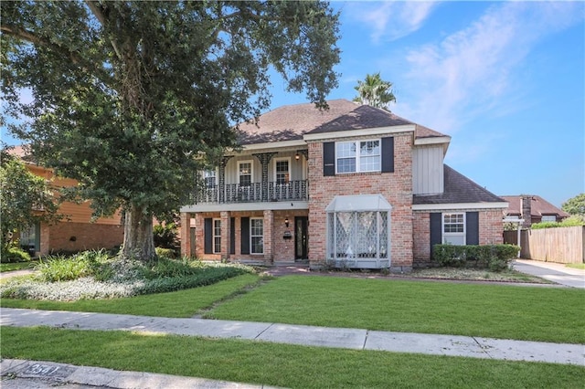 view of front of house with a balcony and a front lawn