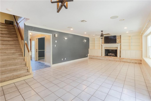 unfurnished living room featuring light tile patterned flooring, ornamental molding, a brick fireplace, built in shelves, and ceiling fan