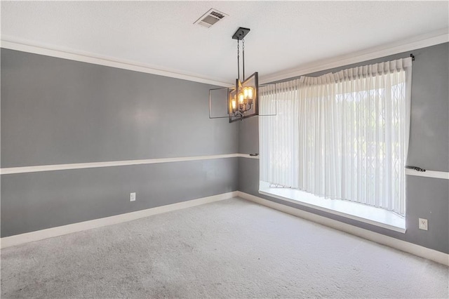 spare room with carpet flooring, crown molding, and a chandelier