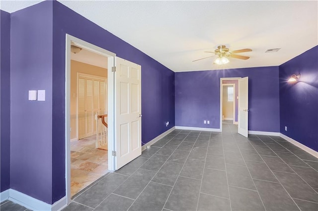 unfurnished room featuring ceiling fan and dark tile patterned flooring