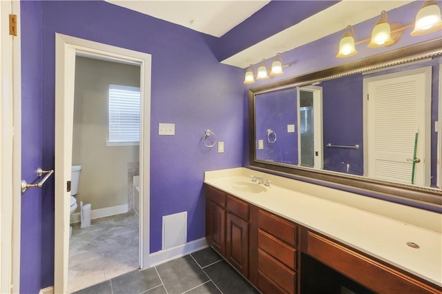 bathroom with toilet, vanity, and tile patterned floors