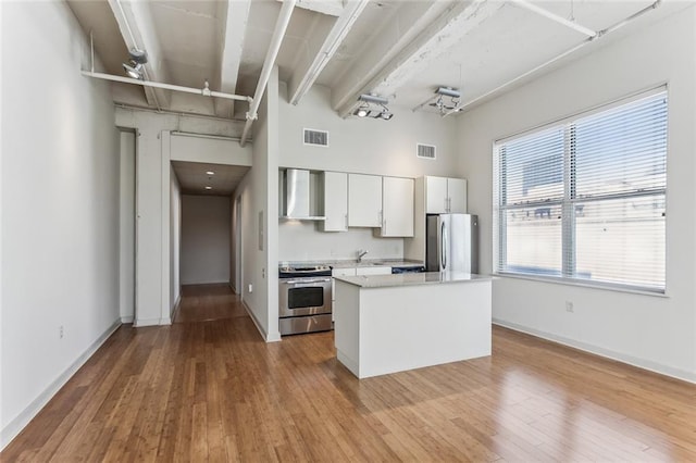 835 Julia St Unit 8, New Orleans, LA 70113 - kitchen featuring stainless steel appliances, wall chimney exhaust hood, light countertops, white cabinets, and a towering ceiling