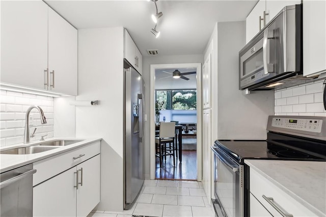 kitchen featuring white cabinets, sink, decorative backsplash, appliances with stainless steel finishes, and light tile patterned flooring