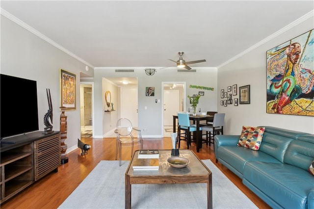 living room with ceiling fan, wood-type flooring, and ornamental molding