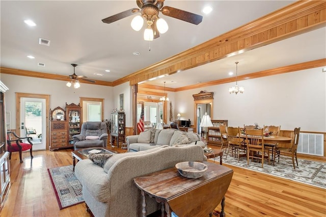 living room featuring ornamental molding, ceiling fan with notable chandelier, and light wood-type flooring