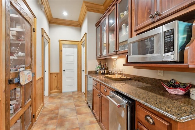 bar featuring light tile patterned floors, ornamental molding, appliances with stainless steel finishes, and dark stone counters