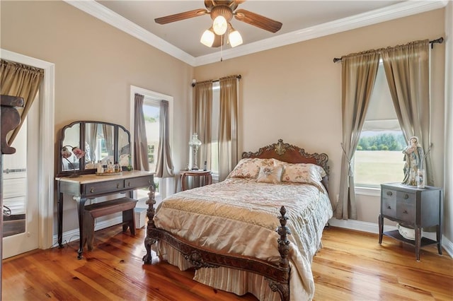 bedroom featuring ceiling fan, light hardwood / wood-style floors, crown molding, and multiple windows