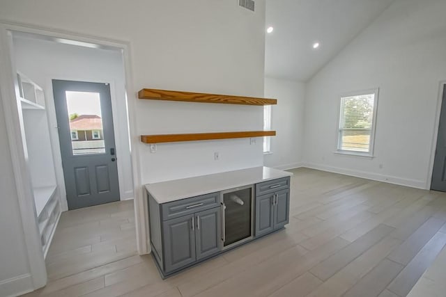 kitchen featuring light hardwood / wood-style flooring, high vaulted ceiling, and gray cabinets