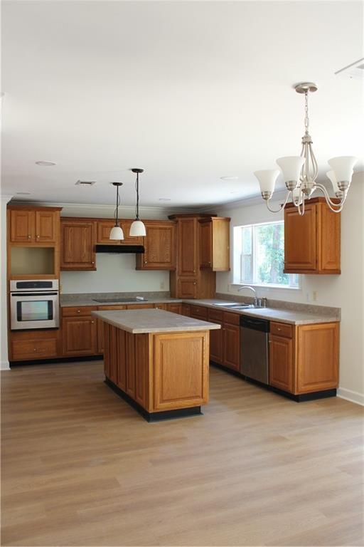 kitchen with an inviting chandelier, pendant lighting, appliances with stainless steel finishes, sink, and light wood-type flooring