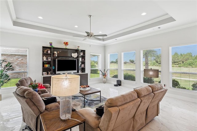 living room featuring a tray ceiling, plenty of natural light, ornamental molding, and ceiling fan