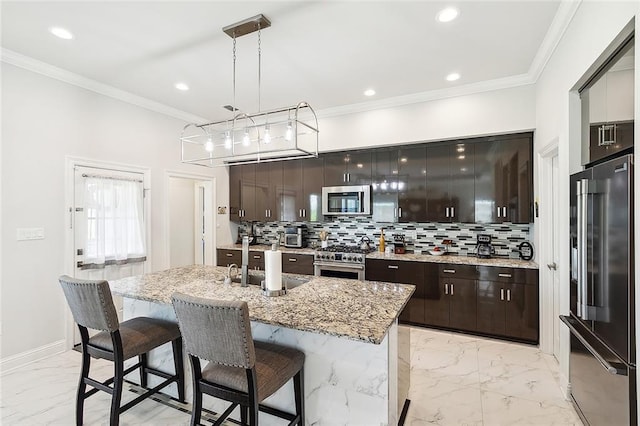 kitchen with premium appliances, dark brown cabinetry, sink, pendant lighting, and an island with sink