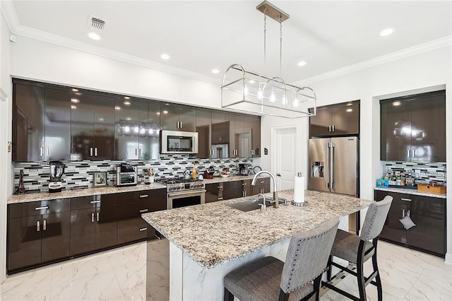 kitchen featuring decorative backsplash, high end appliances, sink, decorative light fixtures, and a center island with sink