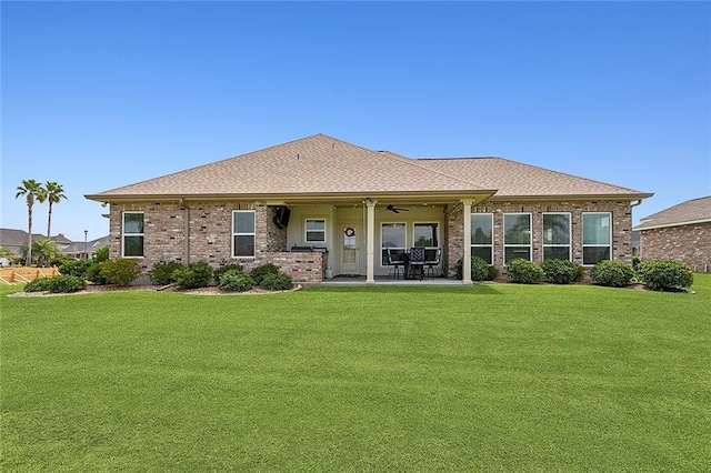 rear view of house featuring ceiling fan, a patio area, and a lawn