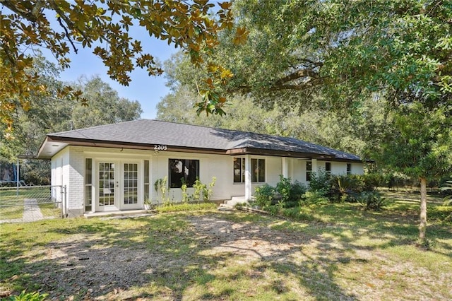 rear view of property featuring french doors and a lawn