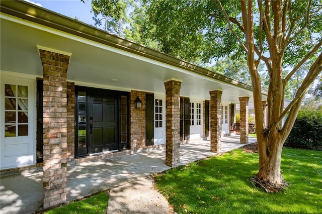 entrance to property featuring a lawn and covered porch