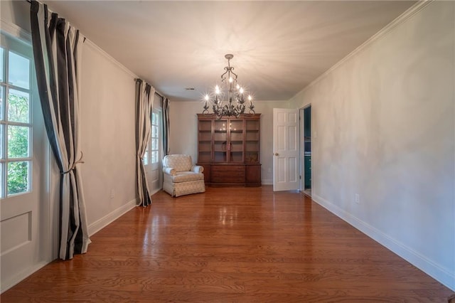 unfurnished room with ornamental molding, a notable chandelier, and dark hardwood / wood-style floors