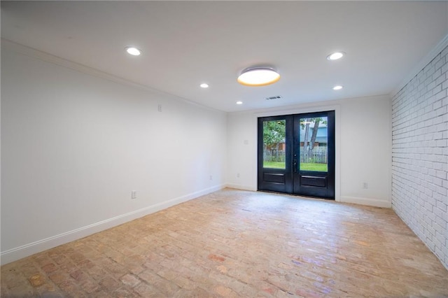 unfurnished room with french doors, brick wall, and crown molding