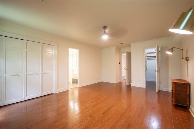 unfurnished bedroom with hardwood / wood-style floors, ceiling fan, and ensuite bath