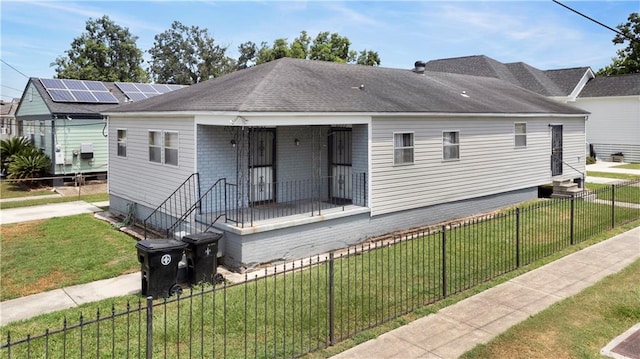 rear view of property featuring solar panels and a yard