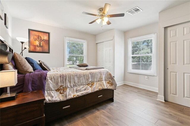 bedroom with ceiling fan, multiple windows, and hardwood / wood-style flooring