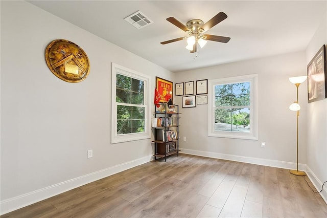 empty room featuring baseboards, visible vents, ceiling fan, and wood finished floors